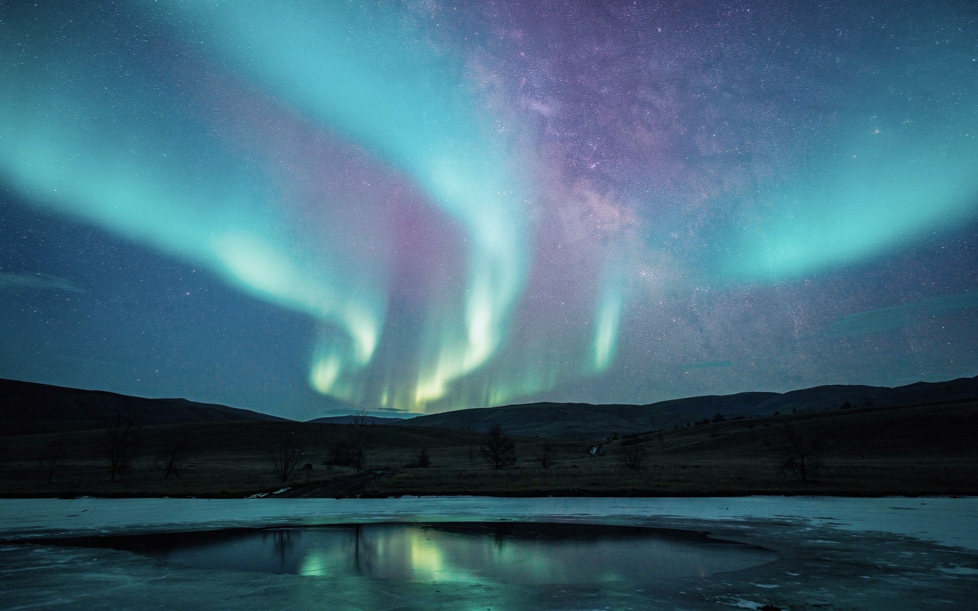 Cyan aurora over frozen landscape